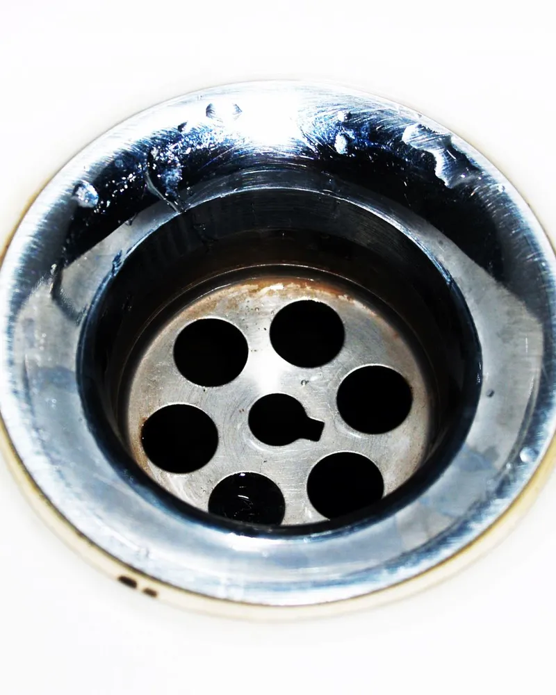 Close-up of a chrome sink drain with water droplets