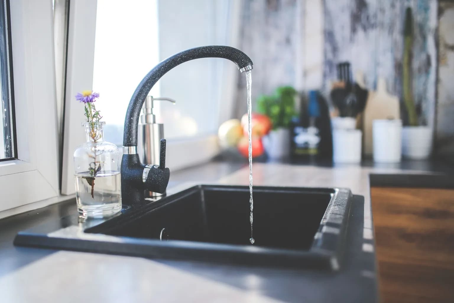 Water running from a black kitchen tap into a sink